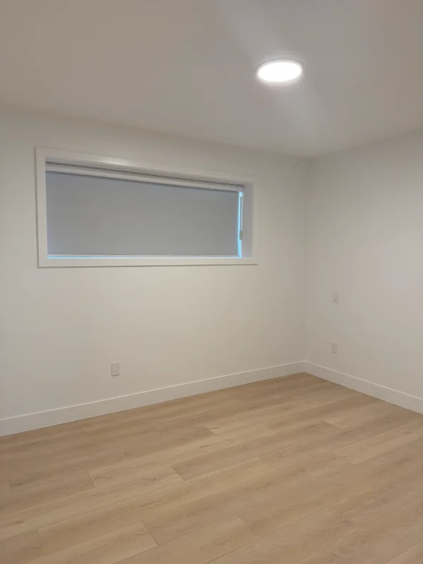 Grey roller shade across a long bedroom transom window